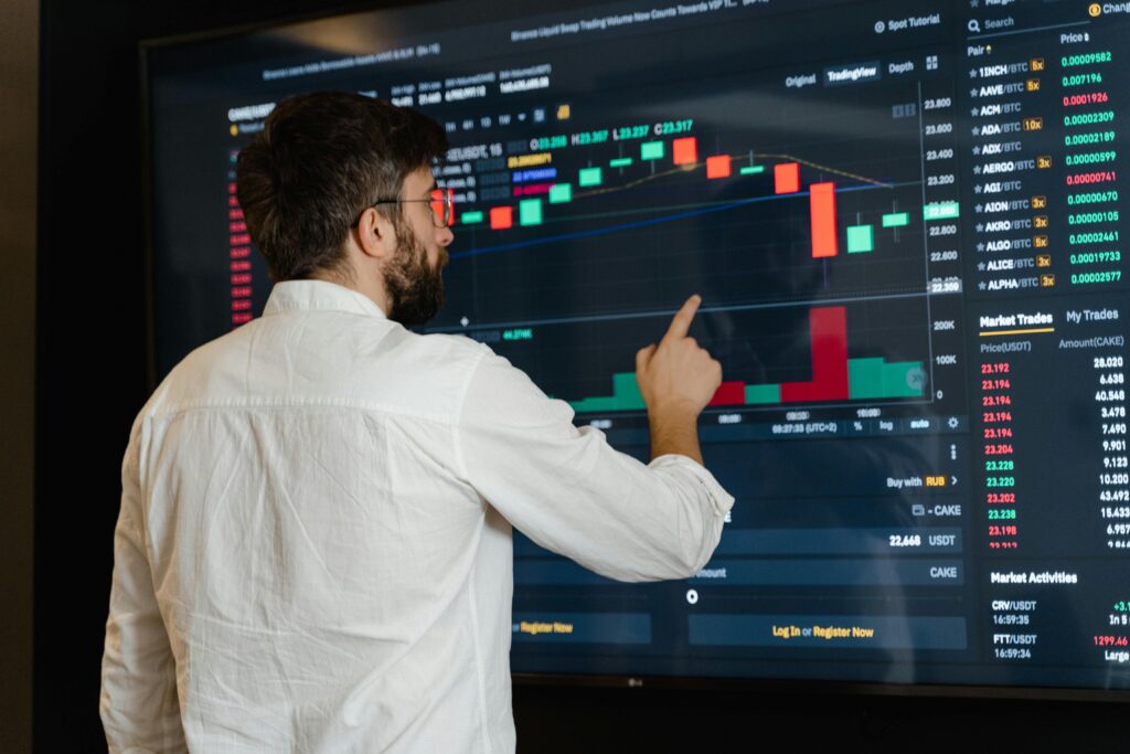 A man analyzes cryptocurrency graphs on a touchscreen monitor in a modern office setting.