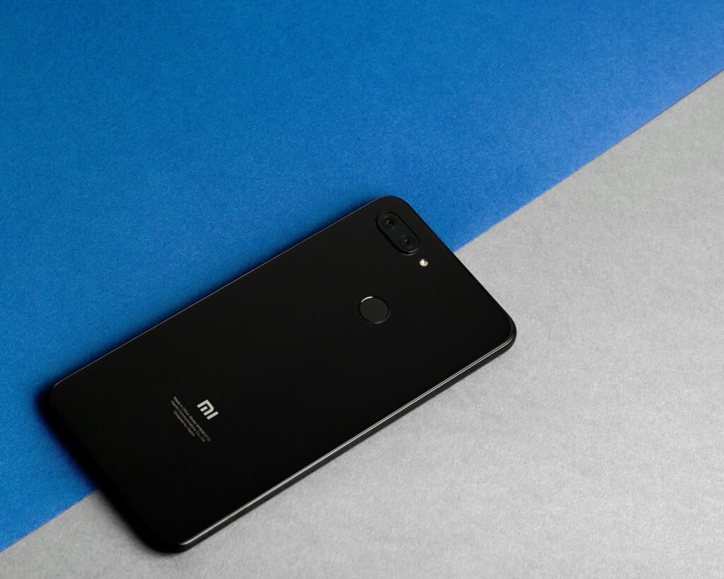 Modern black MI smartphone placed on a blue and gray background, showcasing technology elegance.