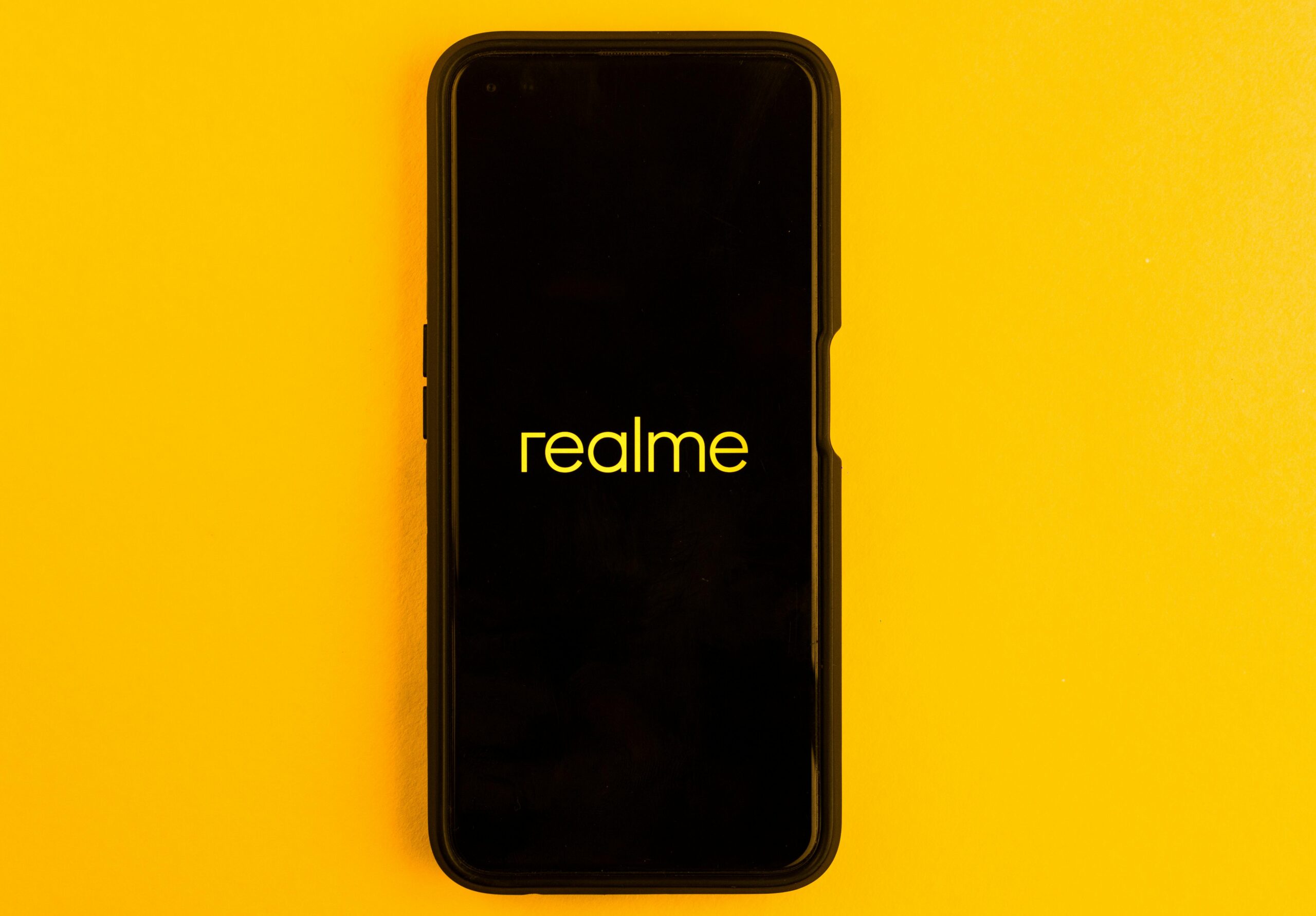 Realme smartphone displayed against a bright yellow backdrop, emphasizing modern technology.